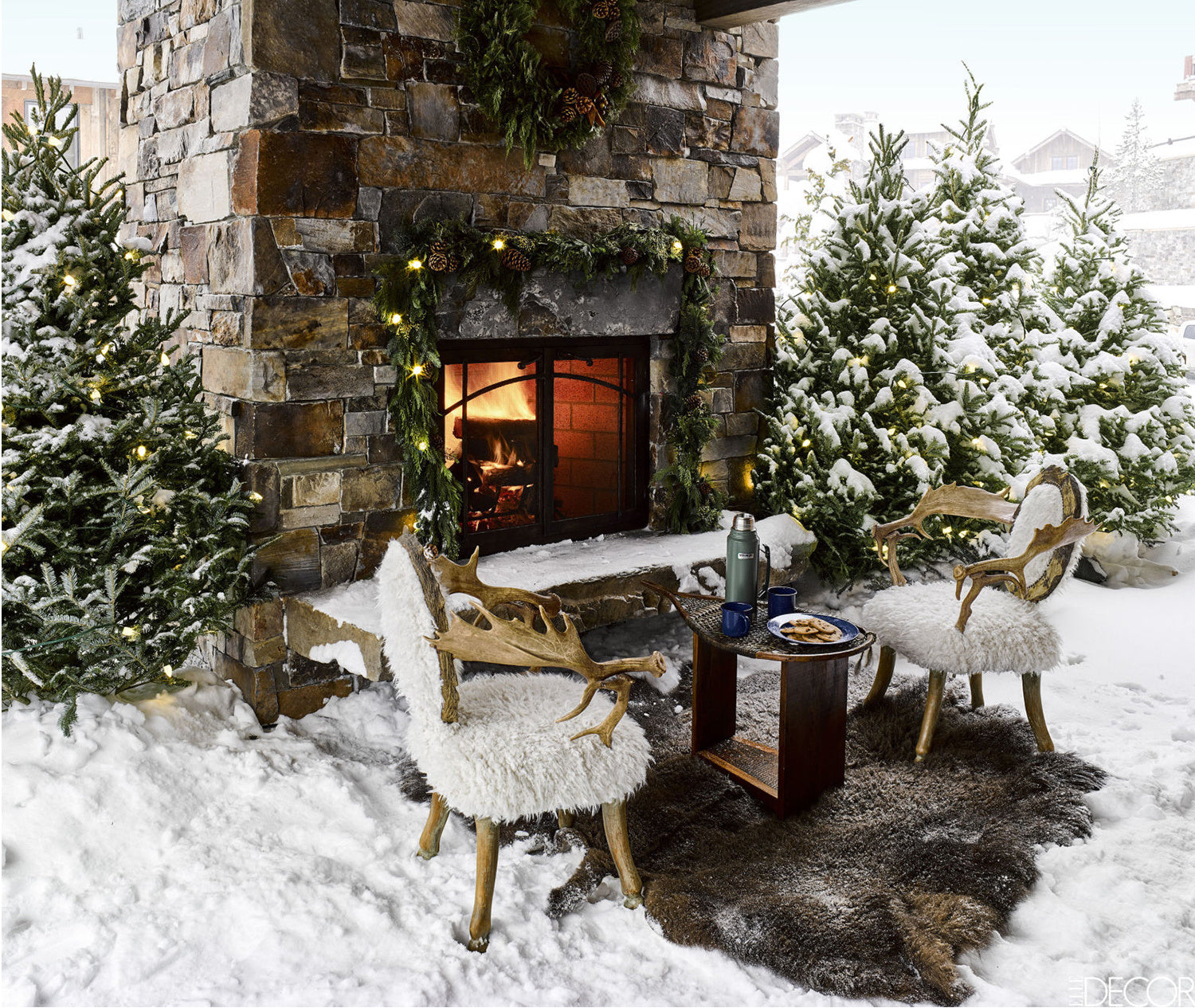 Snowy outdoor fireplace with antler chairs